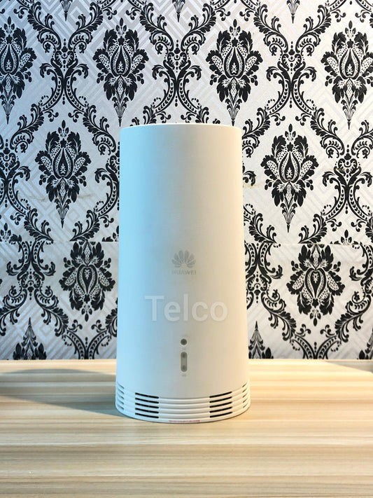 A Huawei N5368X 5G Cpe Max router placed on a table against a wall with a black and white damask pattern.